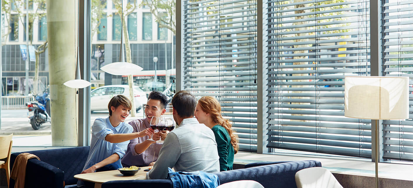 Group of 4 friends sitting in a restaurant raising a toast