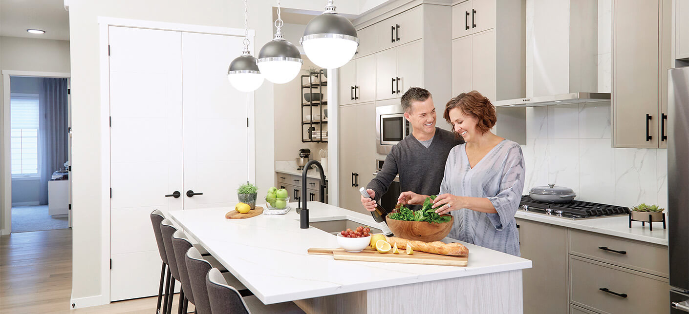 A happy couple preparing a salad in a beautiful kitchen